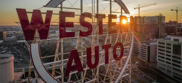 The Western Auto sign above the Crossroads at sunset, with downtown behind it