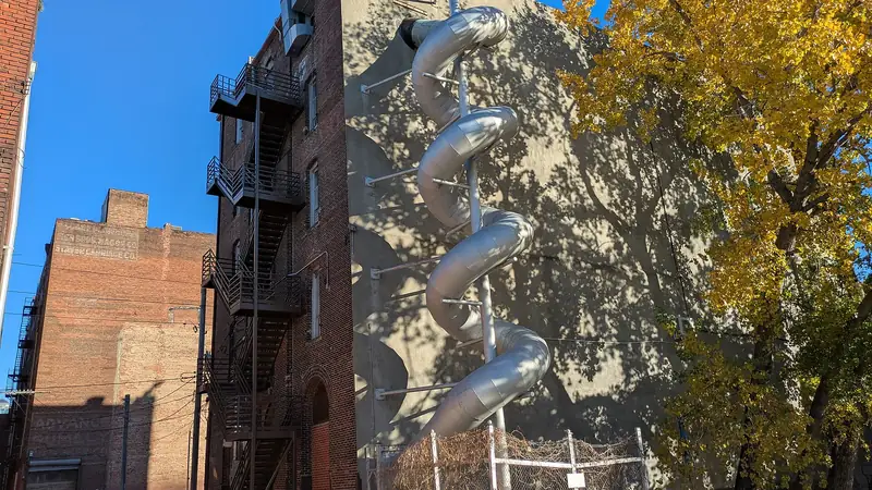 The long silver tube slide winding down the back of the Edge of Hell haunted house building in the West Bottoms
