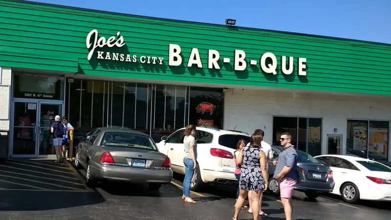 The green Joe's Kansas City Bar-B-Que sign over the original location at 47th and Mission, with people waiting outside