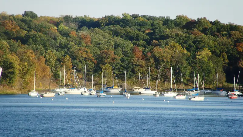 Sailboats moored at the Lake Jacomo marina below wooded hills in Fleming Park