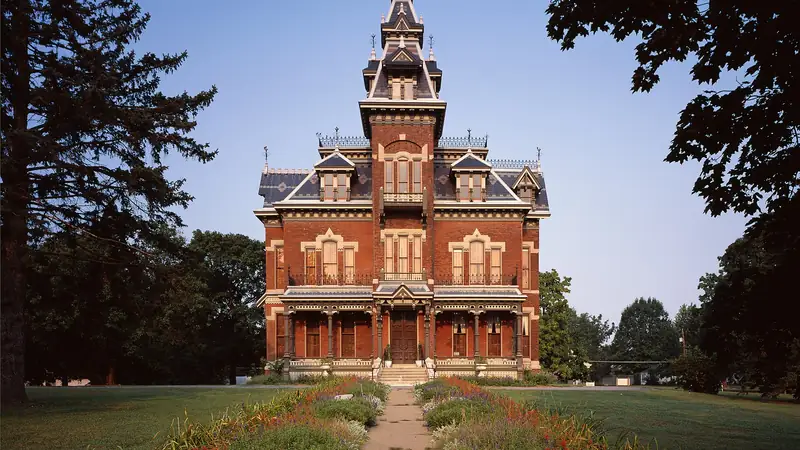 The red brick Vaile Mansion in Independence, with its tall mansard-roofed tower and a garden path to the door