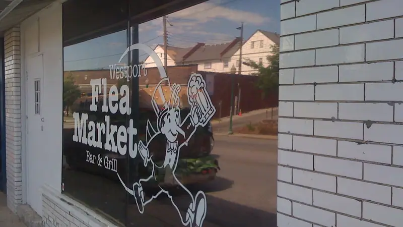 The Westport Flea Market Bar & Grill window sign on a brick wall